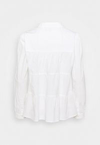 White peplum shirt with long sleeves and a collared neckline. Features gathered sections at the waist and button closures on the cuffs.