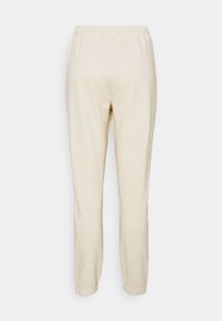 Crème-kleurige, lichte sweatpants met een elastische tailleband en gerimpelde manchetten. Gladde textuur met minimale naden en geen patronen.