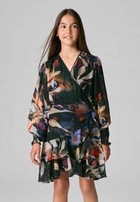 Blommig wrapklänning med långa, ballongärmar och volangkant. Tyget är genomskinligt med en mörkgrön bas och färgglada blommönster.