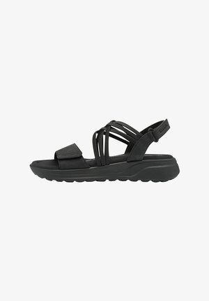 Svart sandal med en bred rem och korsad design. Har en vadderad sula och en sträv gummiyttersula för grepp och komfort.