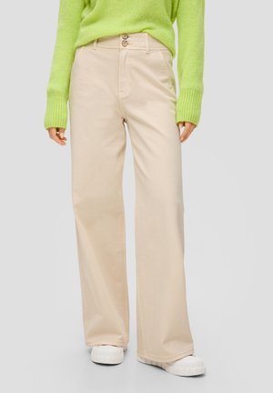 Beige weite Hosen mit glatter Textur, ausgestattet mit zwei Knopfverschlüssen, Vordertaschen, kombiniert mit einem leuchtend grünen Strickpullover.