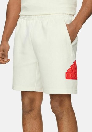 Pantalones cortos deportivos blancos hechos de material suave, con un logo rojo de Adidas en el lado izquierdo y bolsillos laterales, además de una cintura elástica.