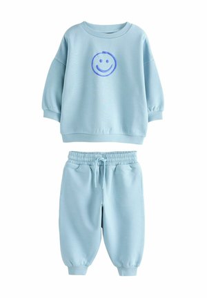 Jasnoniebieska bluza z długim rękawem i pasujące dresy, wykonane z miękkiego materiału. Bluza ma grafikę niebieskiej buźki. Dresy mają elastyczny pas.