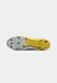 Semelle de chaussures de football avec une finition texturée jaune. Présente six crampons métalliques et une base grise à motif pour une adhérence sur les surfaces en herbe.