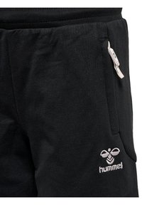 Svarta träningsbyxor i bomull med resårmidja, sidofickor och en vit logotyp på vänster lår. Slät textur.