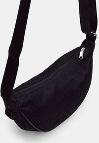 Borsa a spalla nera in rete con chiusura con zip, tracolla corta e design curvo. Superficie testurizzata e dettagli sobri.