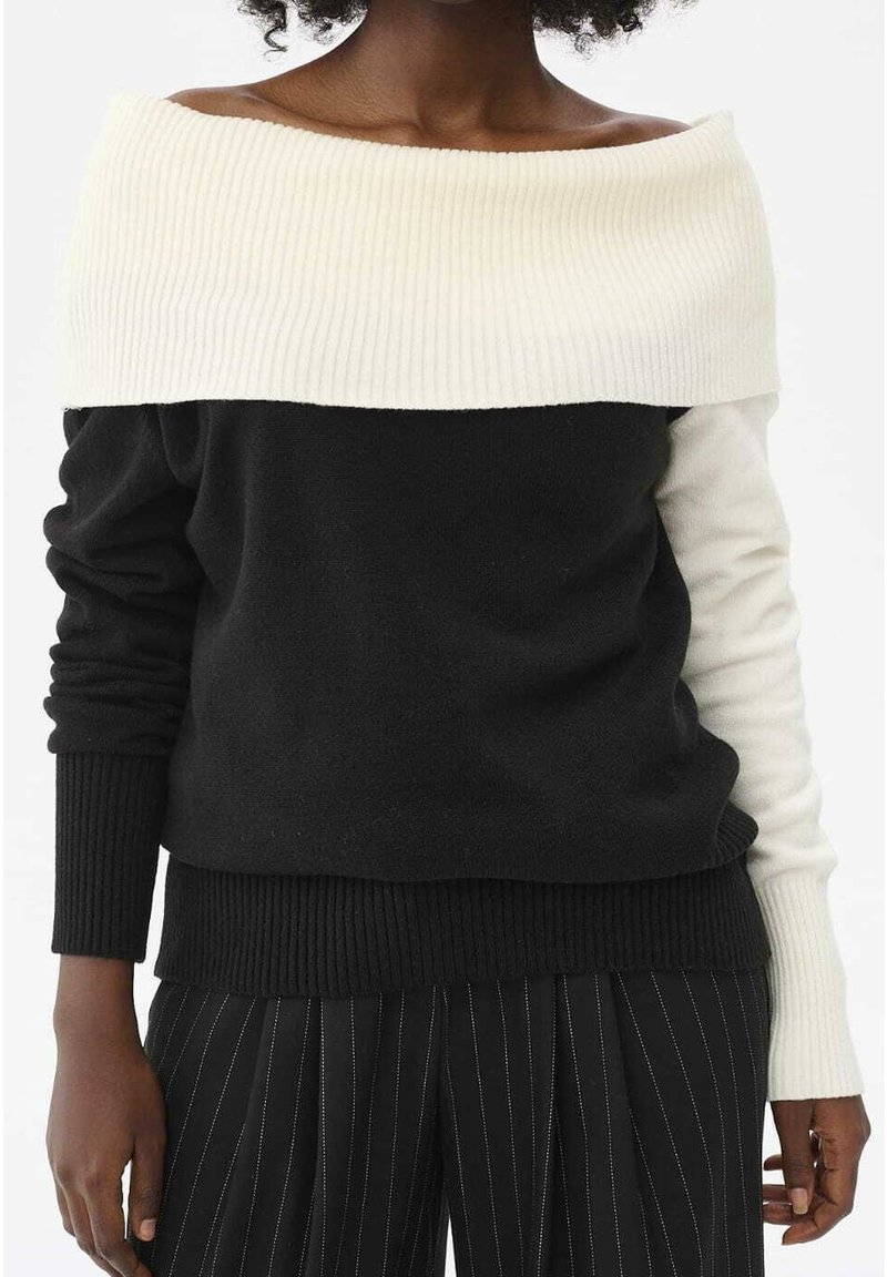 Maglione scollato sulle spalle con una parte superiore bianca a coste e un corpo nero, dotato di maniche lunghe e orlo nero a coste texturizzato.