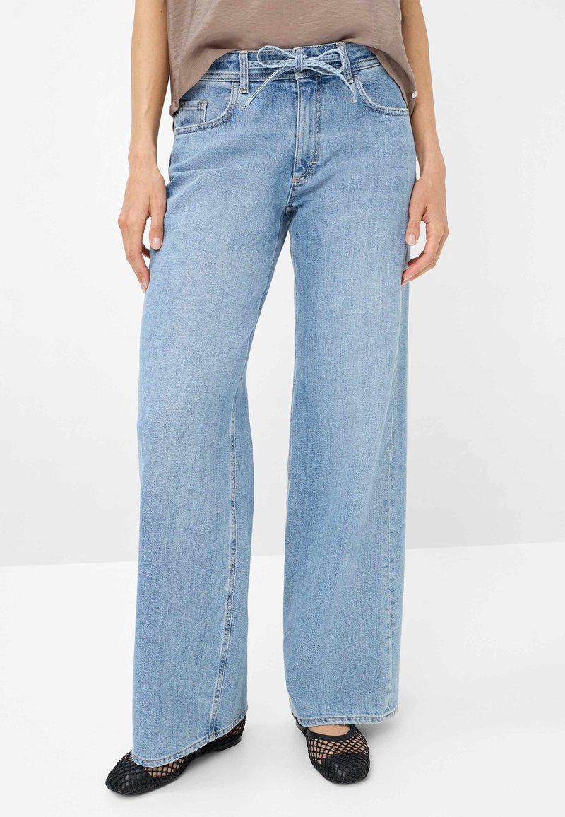 Jeans bleu clair à jambes larges en denim, avec un lien à la taille et deux poches avant. Dotés d'un design classique à cinq poches et d'ourlets bruts.