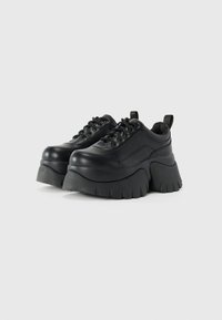 Sorte platform sneakers lavet af glat læder, med en kraftig sål med rillede detaljer og traditionelt snørebåndsdesign.