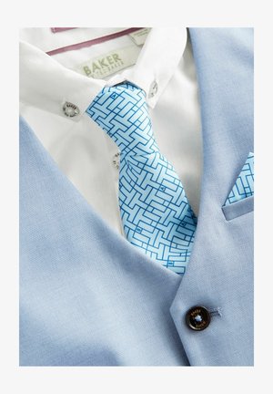 Sinine ülikonna vest peene tekstuuriga, valge särgi, millel on sile viimistlus, ja geomeetriliste mustritega helesinine lips.