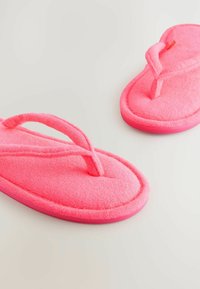 Lyserøde fleece slippers med struktureret overdel, bløde stropper, oval form og tykke, polstrede såler. Lav profil med afrundede kanter.