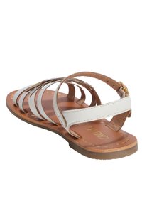 Sandalo bianco in pelle con più cinturini, punta rotonda e suola marrone. Presenta una fibbia in tono oro e un sottile dettaglio perforato.
