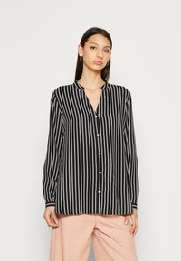 Black and white striped button-up shirt with a V-neck collar and long sleeves, featuring a soft fabric and button detailing.
