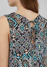 Ärmelloses Kleid mit einem geometrischen Muster in Schwarz, Türkis und Beige. Verfügt über eine Rückenöffnung in Form eines Schlüssellochs mit einem gebundenen Detail.