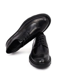 Zwarte leren brogue schoenen met ingewikkelde perforaties, ronde neus en vetersluiting. Dikke, gestructureerde rubberen zool voor duurzaamheid.