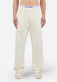 Pantalones de chándal de felpa blanca con una cinturilla elástica que presenta un logo negro de "PEGADOR". Corte holgado con bolsillos laterales y una textura suave.