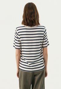 Striped t-shirt with navy and white horizontal stripes, short sleeves, crew neck, and relaxed fit. Soft fabric with subtle texture.