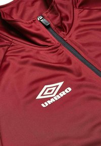 Röd sportjacka av slätt syntetiskt material, med full dragkedja och en vit logotyp. Texturerad yta med en figurvänlig design.