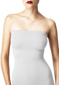 Hvid stropløs top, glat stof, kropsnær design, sømløse kanter, minimalistisk stil, båret mod en lys baggrund.