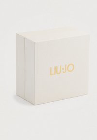Hvid tekstureret rektangulær boks med guld "LIU·JO" logo centreret på fronten, sat mod en simpel lys baggrund.