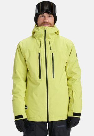 Veste de ski imperméable jaune avec un col haut, des zips noirs et deux poches sur la poitrine. Accents noirs sur les poignets et la capuche.