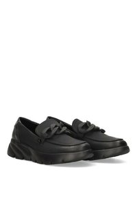 Zapatos informales de cuero negro con punta redondeada, adornos de lazo decorativos en la parte superior y una suela gruesa y texturizada para mayor comodidad.