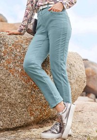 Lichtblauwe broek met een rechte pasvorm, voorzien van zijzakken. Gecombineerd met metallic zilveren sneakers en een patroon top.