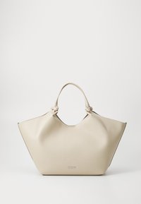 Beige lærveske med en unik vinklet form, som har knyttede håndtak og en subtil logo-detalj i sølv på forsiden.