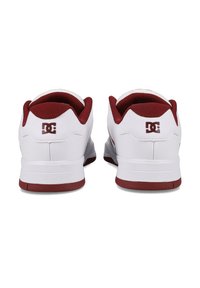 Biele tenisky s červenými akcentmi, s hladkým vrchným materiálom, polstrovaným golierom a textúrovanou gumovou podrážkou. Logo zobrazené na päte.