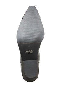 Semelle de chaussure noire à bout pointu avec des zones de grip texturées et un petit logo métallique près de la partie talon.