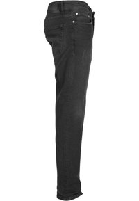 Jeans de mezclilla negros con corte ajustado, bolsillos laterales, detalle sutil de arrugas y una cintura estándar que incluye remaches de metal.