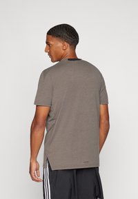 Grey short-sleeve t-shirt with a crew neck, made of soft material. Features a black accent at the back neckline and side slits.