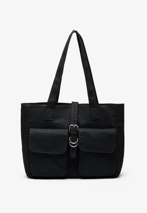 Zwarte canvas tote bag met twee voorzakken, verstelbare band met metalen gesp, rechthoekige vorm, stevige handvatten en net gestikte naden.