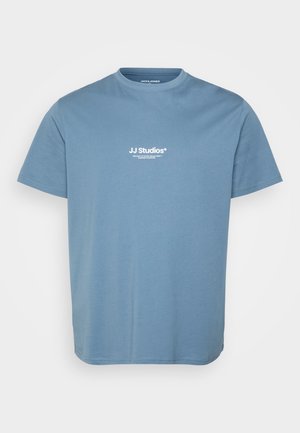 Hellblaues T-Shirt mit kurzen Ärmeln und weißem Textlogo "JJ Studios" auf der Brust zentriert, Rundhalsausschnitt und einfachem Baumwollstoff.