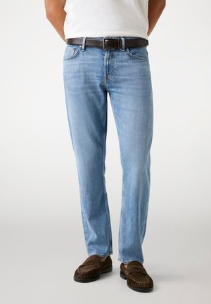 Lichtblauwe denim jeans met een rechte pijp, met voorzakken, een bruine leren riem en bruine moccasin-achtige schoenen.
