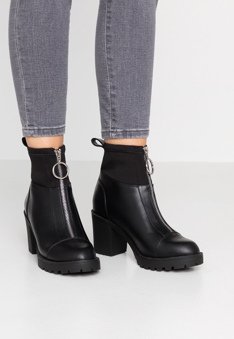 Schwarze Knöchelstiefel mit einem kräftigen Absatz und Reißverschluss. Aus Leder mit einem elastischen oberen Bereich. Strukturierte Sohle für besseren Halt.