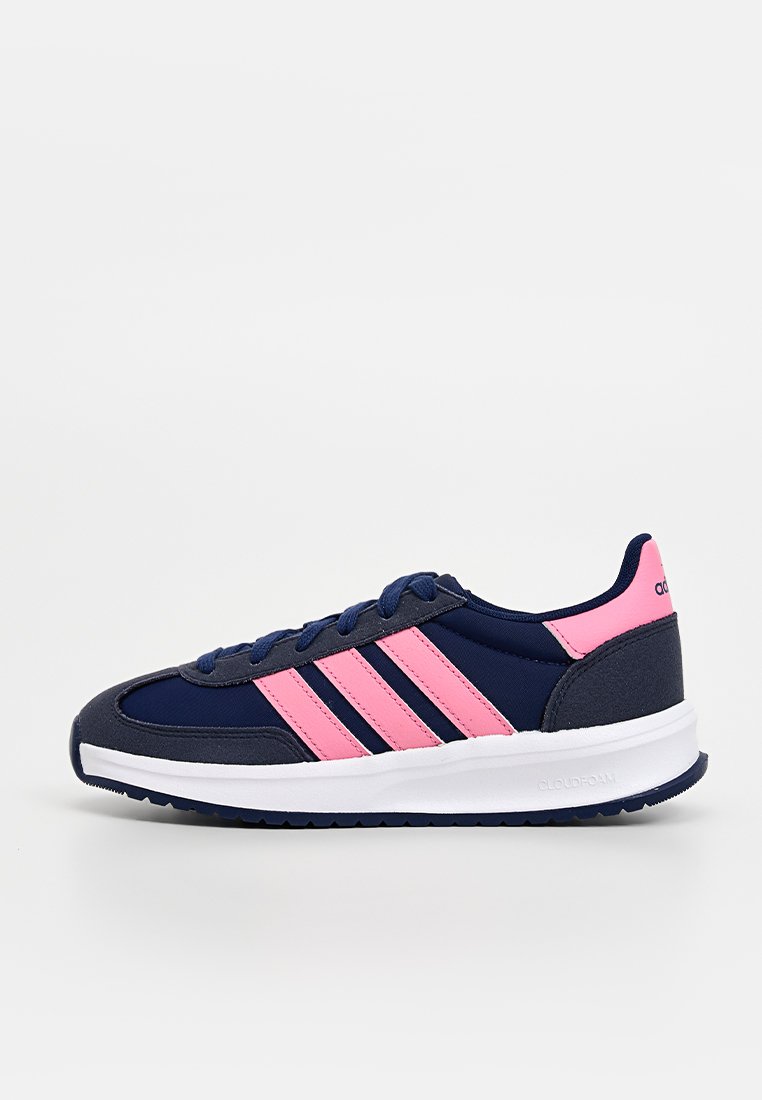 Baskets de sport bleu marine avec des accents roses, trois rayures emblématiques, un col rembourré et une semelle en caoutchouc blanc avec une texture anti-dérapante.