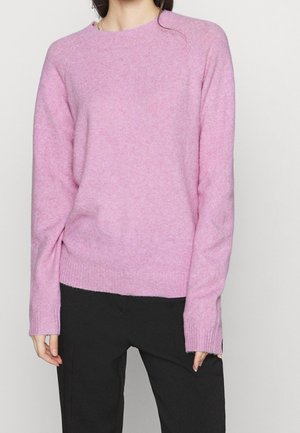 Pink knit sweater with a round neckline and long sleeves, featuring ribbed cuffs and hem. Soft texture, paired with black pants.