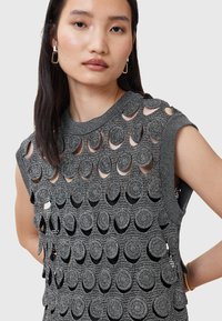 Top gri fără mâneci, cu decupaje circulare, având un design texturat din tricot. Marginile sunt finisate cu un tiv riblat.