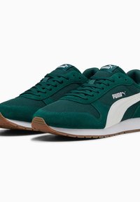 Pantofi sport din suede verde și plasă, cu accente și șireturi albe, având o talpă din cauciuc natural. Logo-ul PUMA se află pe limbă și pe lateral.