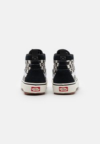 Vysoké tenisky s designem černého semiše a bílého kostkovaného textilu, s gumovou podrážkou a červeným logem na patě.