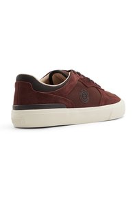 Sneaker in suede bordeaux con design low-profile, suola in gomma crema e dettagli in mesh neri. Presenta un logo sul lato e dettagli testurizzati.