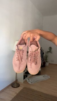 Sapatilhas de atletismo em suede rosa com design de atacadores, bico redondo e marcação em dourado. Superfície texturizada e sola de borracha com um tom neutro.