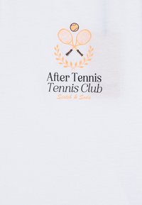 Camiseta de algodón blanca con un estampado en naranja y negro. El diseño incluye raquetas de tenis cruzadas, una pelota de tenis y hojas de laurel.