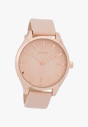 Montre analogique en or rose avec un cadran texturé rose clair, des index en or rose, et un bracelet en silicone rose clair mate.