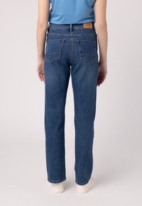Jeans in denim blu con un design a gamba dritta. Presentano due tasche posteriori, un'etichetta in pelle sulla vita e una finitura pulita all'orlo.