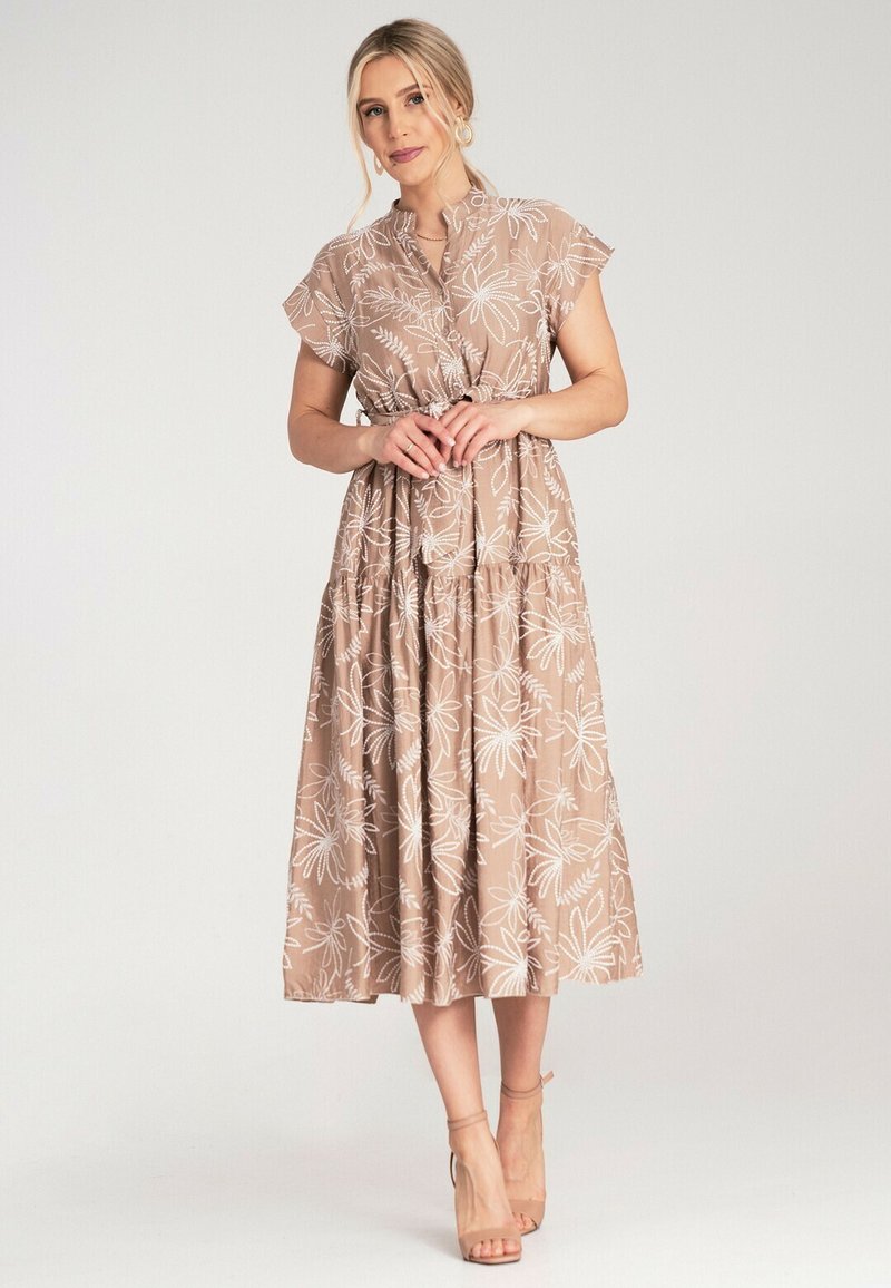 Braun-blumiges Kleid mit kurzen Ärmeln, tailliertem Bund und gestuftem Rock. Hergestellt aus leichtem Stoff mit strukturierten weißen Blumenmustern.