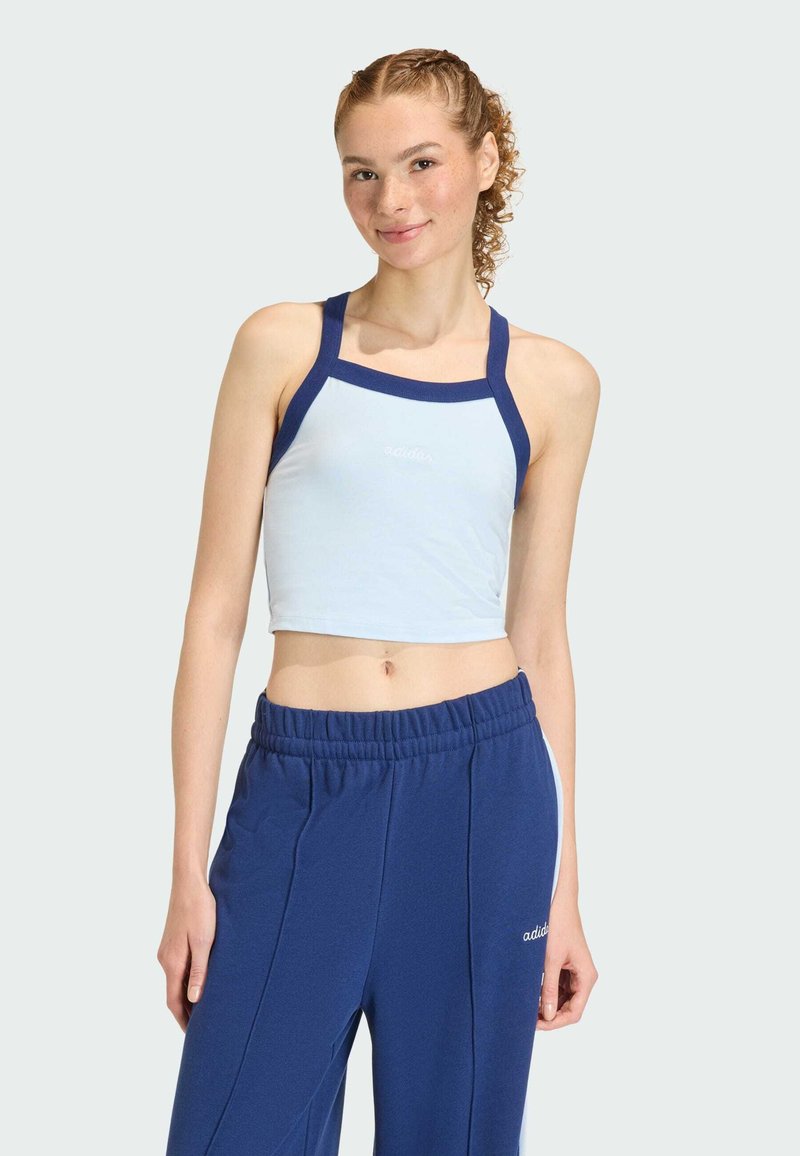 Svijetloplava kratka majica s tamnoplave naramenice, s logotipom. Uparena s tamnoplave trenirkama s elastičnim pojasom i bijelim bočnim detaljima.