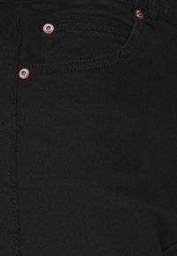 Jeans de mezclilla negra con una textura suave, acentos en tono cobre y un diseño clásico de cinco bolsillos.