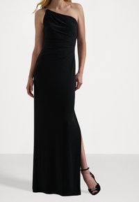 Svart, enaxlad aftonkjol med rynkdetaljer, golvlång design och en sidöppning. Försedd med dekorativ hårdvarudel.